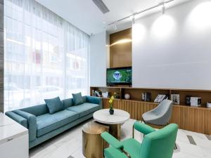 a living room with a blue couch and chairs at Magnotel Hotel Dongxing Guomen Port in Tung-hsing-shih