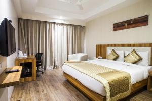 a hotel room with a bed and a desk and a television at Le Roi Udaipur in Udaipur