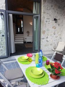 einen weißen Tisch mit grünen Platten und Blumen darauf in der Unterkunft Casa Limonaia San Rocco in Limone sul Garda