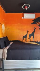 a bedroom with a mural of giraffes on the wall at Oceans Bavarian Boutique Apartments in Maun +12 photos