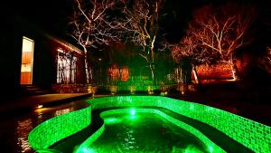 a pool with green lighting in a yard at night at 北京丛林里野奢汤泉酒店 in Huairou