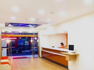 un homme est assis à un comptoir dans un bureau dans l'établissement 7 Days Inn Jinggangshan Scenic Spot, à Jinggangshanzonghekenzhichang