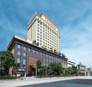 un grand bâtiment avec une enseigne au sommet dans l'établissement Vienna International Hotel Dongguan Changping Tian'ehu Road, à Dongguan