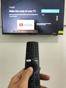 une personne tenant une télécommande devant une télévision dans l'établissement Dehome near Pakuwon Mall (Syariah), à Surabaya