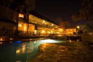 a swimming pool in front of a building at night at Maun Lodge in Maun