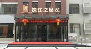 a building with an entrance with chinese writing on it at Jinjiang Inn Select Qingdao West Coast Coach Exhibition Center High-Speed Railway Station in Huangdao