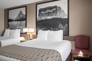 a hotel room with two beds and a chair at Super 8 by Wyndham Lewistown in Lewistown