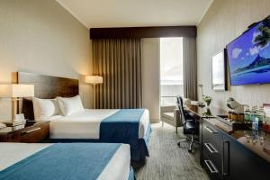 a hotel room with two beds and a desk at Wyndham Santiago Aeropuerto in Santiago