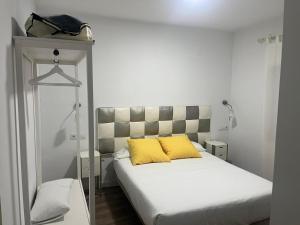 Un dormitorio con una cama con una almohada amarilla. en Apartamentos La Encomienda 2 Llaves, en Moraleja
