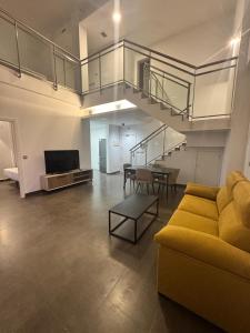 a living room with a yellow couch and a staircase at Palm Suites Gran Vía in Alicante