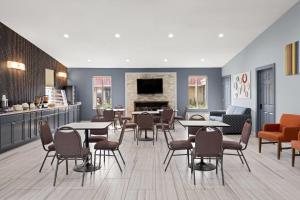 a waiting room with tables and chairs and a fireplace at Super 8 by Wyndham Fort Wayne in Fort Wayne