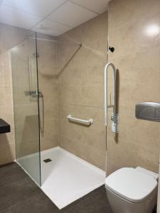 a bathroom with a glass shower with a toilet at Palm Suites Gran Vía in Alicante +18 photos