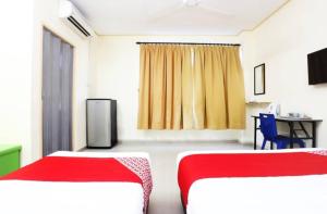 a room with two beds and a table and a desk at Pelangi Marang by Tanjung Sukai in Marang +11 photos