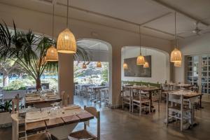 restauracja ze stołami i krzesłami oraz dużymi oknami w obiekcie Hotel Cala Joncols w mieście Roses