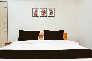 a bedroom with a white bed with three pictures on the wall at FabHotel Keshava Executive in Pune +19 photos
