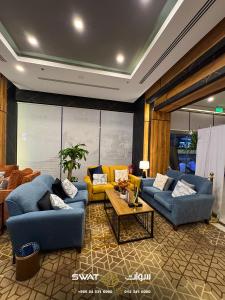 Una sala de estar con dos sofás azules y una mesa. en سوات للشقق المخدومة 5, en Al Khobar