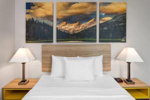 a bedroom with a bed with three paintings on the wall at Days Inn & Suites by Wyndham Spokane Airport Airway Heights in Airway Heights +24 photos