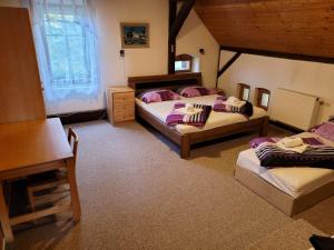 a bedroom with two beds and a table and a window at Chalupa V kopci in Vysoká Srbská +26 photos