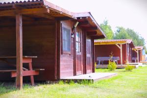 a small wooden cabin with a porch in a field at SP camping Spāres Prieduļi in Nīca +138 photos
