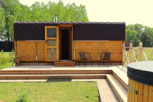 a tiny house with a patio and a table at SP camping Spāres Prieduļi in Nīca