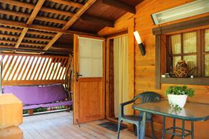 a porch of a cabin with a table and a bed at SP camping Spāres Prieduļi in Nīca