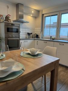 エアフトシュタットにあるFerienwohnung Weitblickのキッチン(木製テーブル、皿、グラス付)