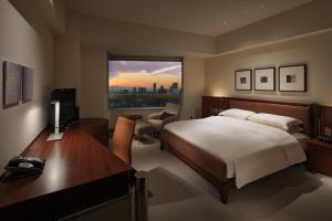 a bedroom with a bed and a desk and a window at Grand Hyatt Tokyo in Tokyo