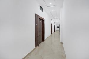 バラナシにあるCollection O Banaras Railway Junction Formerly Varanasi Suitesの白い壁と木製のドアのある廊下