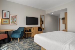ポート・クリントンにあるHampton Inn & Suites By Hilton Port Clinton Catawba Islandのベッドと椅子とテレビがあるホテルの部屋