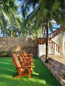 a group of chairs sitting on a lawn with palm trees at J's PALM BEACH Resort in Batangas City