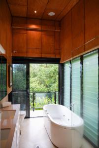 a bathroom with a tub and two toilets and a window at The Cassowary - Luxury Rainforest Retreat in Cassowary