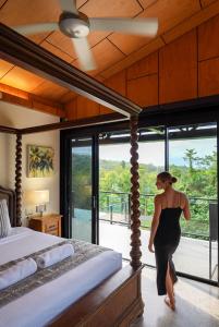 a woman in a black dress walking in a bedroom at The Cassowary - Luxury Rainforest Retreat in Cassowary