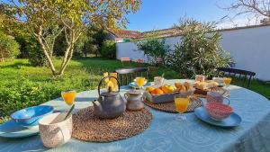 a table with a blue table cloth with food and orange juice at Jolie maison avec parking et jardin au cœur de Loix in Loix