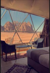 une chambre avec un lit, une table et des chaises dans l'établissement WADI RUM TARA lUXURY CAMP, à Wadi Rum