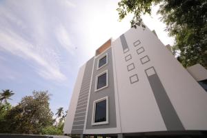 a tall white building with trees in front of it at The Base Inn in Puducherry