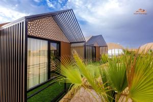 a modern house with palm trees in front of it at Desert Rose Village in Al Khatim