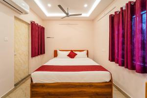 a bedroom with a bed with red curtains at VSA Residency in Pūrnānkuppam