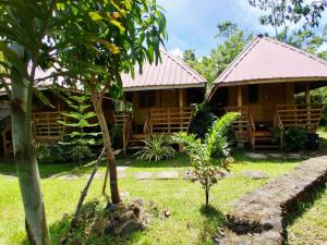 a wooden house with a garden and a tree at B&R Hostel in Puerto Princesa City