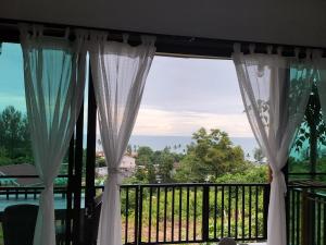 a window with curtains and a view of the ocean at Baan Seaview Sunset in Phra Ae beach