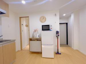 a kitchen with a refrigerator and a clock on the wall at star house akihabara ueno tokyo in Tokyo
