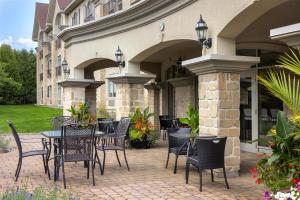 a patio with tables and chairs in front of a building at Hotel Vallea Bromont, Tapestry Collection by Hilton in Bromont