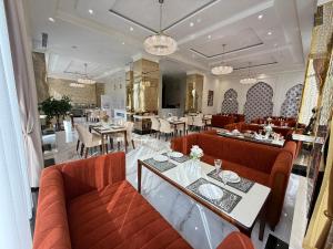 a restaurant with red couches and tables and chairs at Khorazm Hotel in New Uzbekistan Park in Teshabayguzar