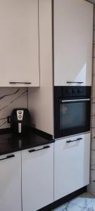 a kitchen with white cabinets and a black microwave at Myhouse in Ariana