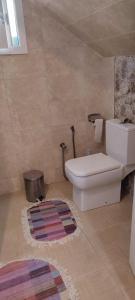 a bathroom with a toilet and a rug at Myhouse in Ariana