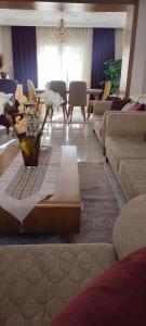 een woonkamer met banken en een tafel met bloemen erop bij Myhouse in Ariana