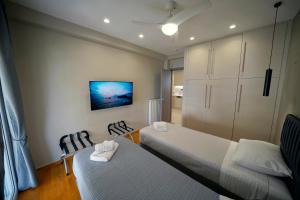 a bedroom with two beds and a tv on the wall at POSEIDON Executive Suite in Athens