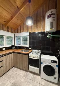 une cuisine avec une cuisinière et une machine à laver dans l'établissement Marías del Carmen, à San Martín de los Andes 6 autres photos