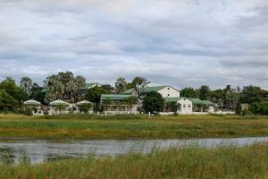 a group of houses in a field next to a body of water at Maun Lodge in Maun