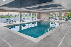 a swimming pool with tables and chairs in a building at Home2 Suites By Hilton Frankenmuth in Frankenmuth