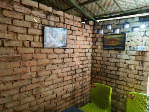 Habitación con 2 sillas verdes y pared de ladrillo en Mr freedom hostel, en Pushkar